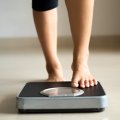 A woman's lower legs stepping onto weighing scales.
